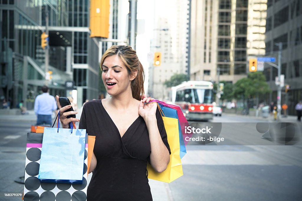 Young Woman Shopping Young attractive woman reading text message on her cellphone while shopping. Adult Stock Photo