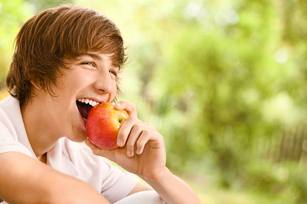 Cheerful boy eating an apple