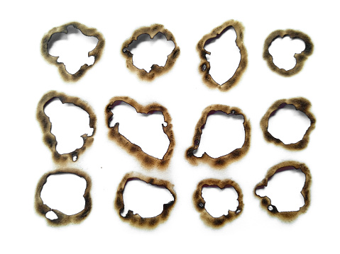 Fire holes in white paper. Collection of burnt holes in a piece of paper isolated on white background. Burnt paper on white background