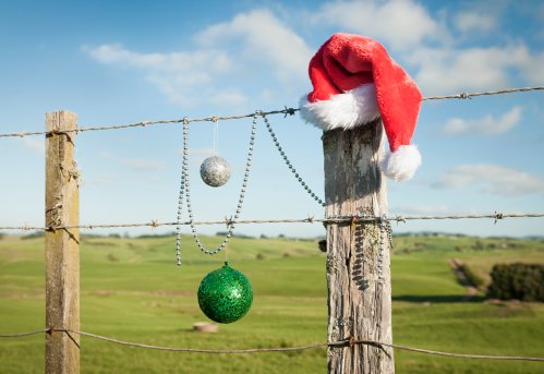 Christmas in summer - a red santa hat and Christmas decorations on a fence in rural New Zealand, taken in December.