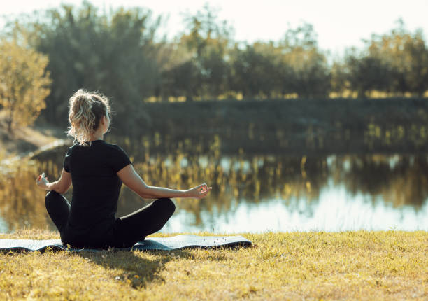 a young girl meditates by the river's edge
