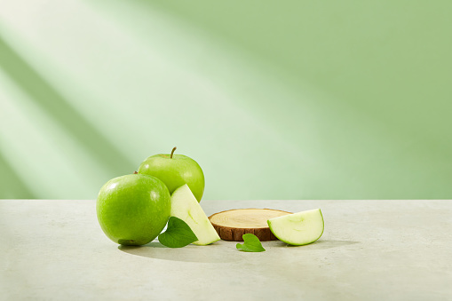 Healthy fruit concept with round-shaped podium arranged on the plate with green apple surrounded. Vacant space to display natural beauty product extracted from Green Apple (Malus domestica)