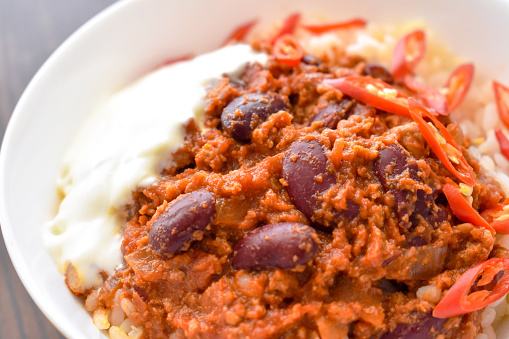 Chilli con carne with rice in a white bowl. Traditional Mexican food.