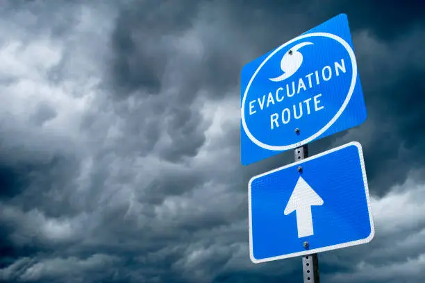 A Directional Sign in Front of Storm Clouds indicating the Storm Evacuation Route.