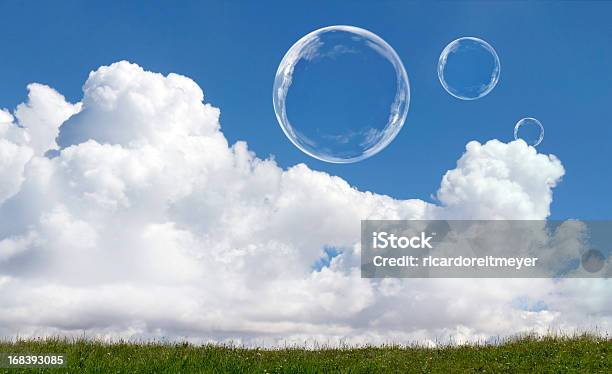 Foto de Bolhas De Sabão Flutuando Bem Iluminado Contra O Céu Azul E Nuvens e mais fotos de stock de Bolha - Estrutura física