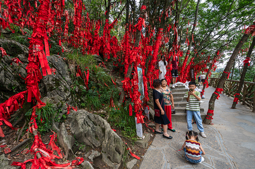 Zhangjiajie, China - August 30, 2023 :A family near red ribbons with Chinese symbols in the Wishing Forest of Zhangjiajie National Park, Tianmen Mountain.