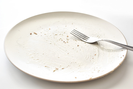 Dirty plate with a fork on the table. Photo can be used for the concept of how to clean the plate after food.