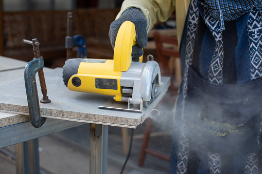 Worker using a grinding machine for cut cement board.