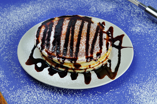 Delicious pancakes with chocolate syrup on textured background