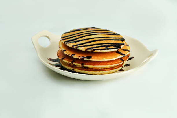 Delicious pancakes with chocolate syrup on white background