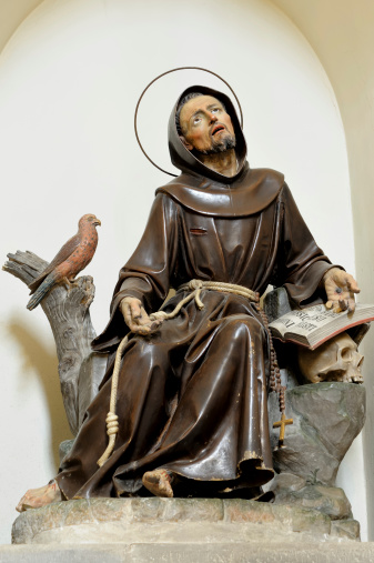 La Verna, Tuscany, Italy: statue of saint Francis made by Giovanni Collina Graziani (1820-1893). This statue is placed in the Chapel of the Stigmata church inside the La Verna sanctuary. On the left, the bird (rook) that woke up the saint overnight in order to pray.