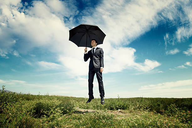 istock Young business man jumping in nature with umbrella 168399420