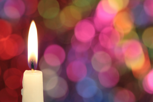 Candle on a defocused glittering lights background.