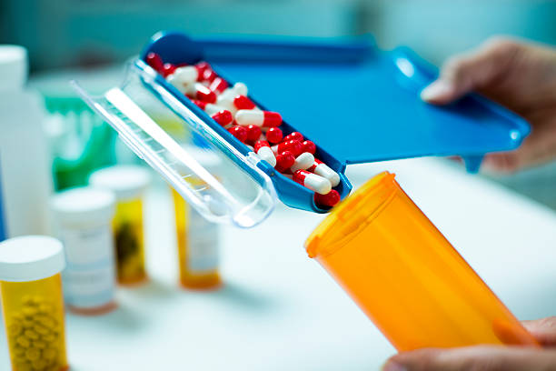 balcão de comprimidos com recheio frasco de comprimidos cápsulas - pharmacist pharmacy pill medicine - fotografias e filmes do acervo