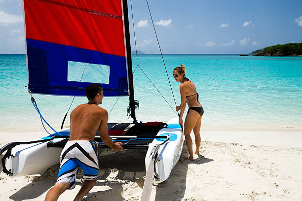 istock couple pushing catamaran into water to go sailing 168410355
