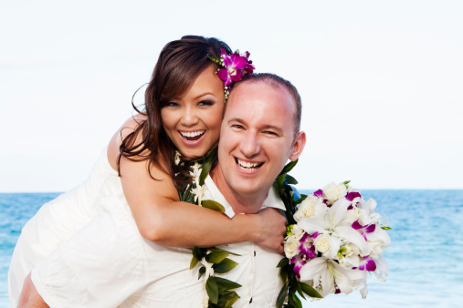 Portrait of a happy young couple who were just married on a Hawaiian beach.