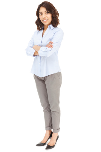 Photo of an attractive young Hispanic businesswoman in blue button-down shirt, standing with arms folded; isolated on white.