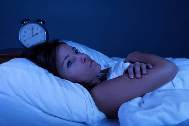 Insomnia Photo of a young woman suffering from insomnia. Blue night time effect created with blue gel over studio lighting. insomnia photos stock pictures, royalty-free photos & images
