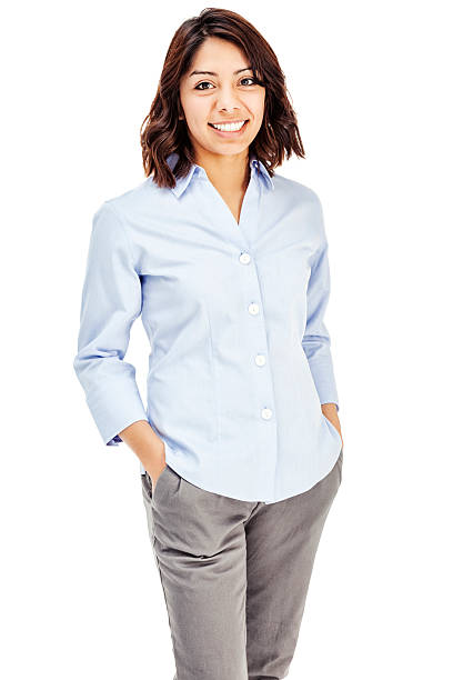 Attractive Young Hispanic Businesswoman Photo of an attractive young Hispanic businesswoman in blue button-down shirt, standing with hands in pockets; isolated on white. mid length hair stock pictures, royalty-free photos & images