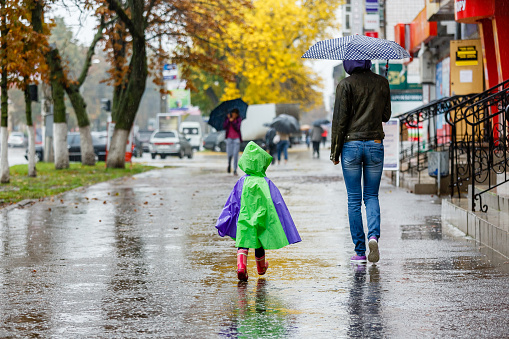 mother and child walk in the city with an umbrella in the rain.
