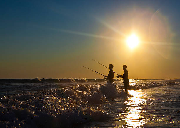 Father and Son Surf Fishing on the Gulf Coast Father and son enjoying fishing at sunset on the Gulf Coast. sea fishing stock pictures, royalty-free photos & images