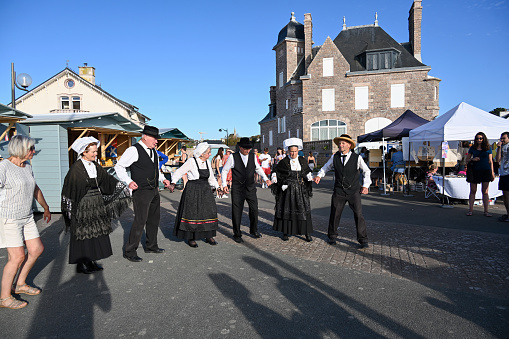 Erquy, Brittany, France, August 21, 2023 - Traditional Breton dance group at summer market / evening market in downtown Erquy, Brittany.