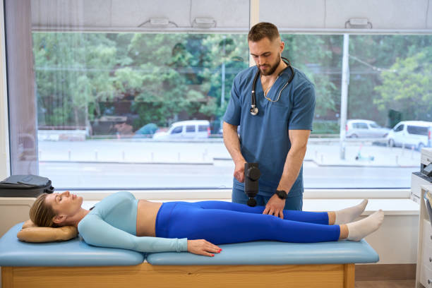 istock High-qualified man osteopath massaging female sore knee with percussion massager 1684202153
