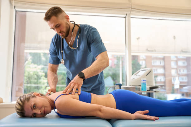 istock Woman lying on couch while therapist doing extracorporeal shock wave therapy 1684205389