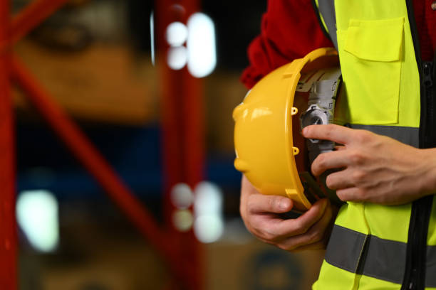 istock Unrecognizable male warehouse worker holding hardhat standing aisle between rows of tall shelves full of packed boxes 1684213625