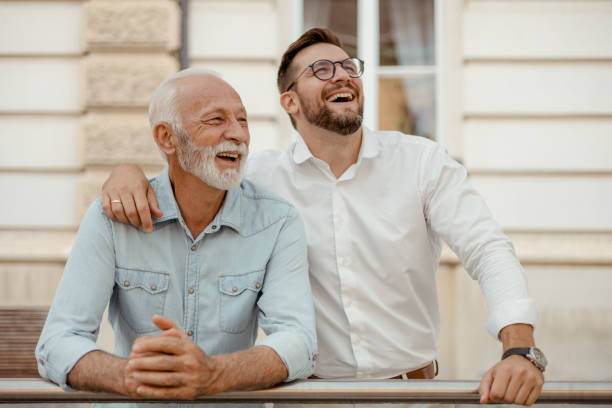 We always share a good laugh Happy Senior Father and Adult Son Having Friendly Positive Conversation on the City Street father son grandfather fathers day stock pictures, royalty-free photos & images