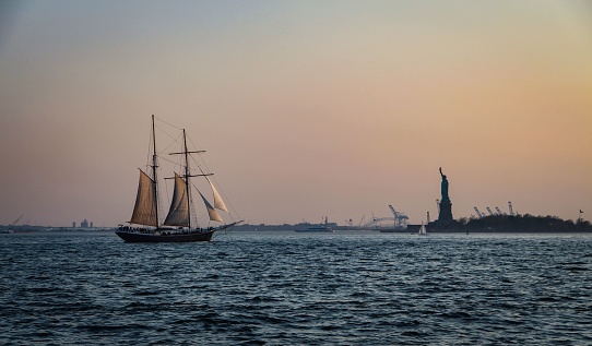 A sailboat sailing towards the Statue of Liberty, located in New York Harbor in the United States.