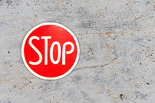 Red stop sign vintage for traffic control on cement wall background.