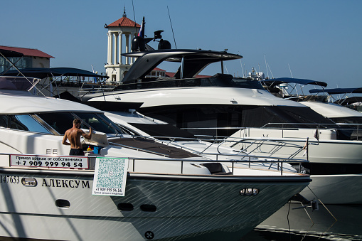 white yachts stand at the pier in the city port on a sunny summer day in Sochi, Krasnodar Krai