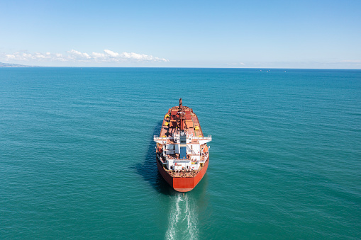 Aerial view of a heavy loaded cargo vessel traveling over calm, blue sea.