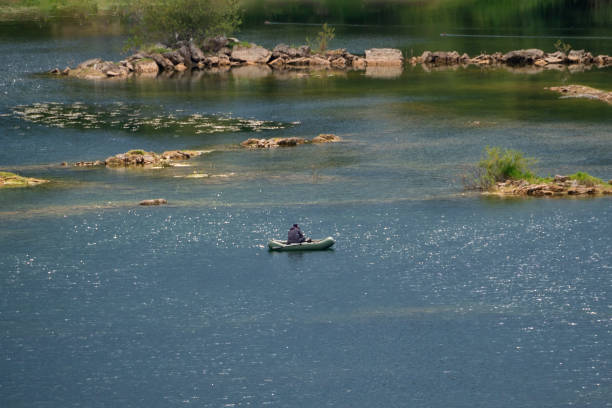 istock Fisherman floats down the blue river in an inflatable boat, catching fish. 1684254602