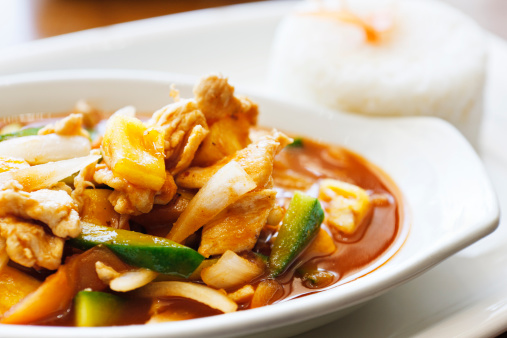 The Thai version of sweet and sour chicken with chilli, pineapple, cucumber and onions. A mound of rice sits in the background.