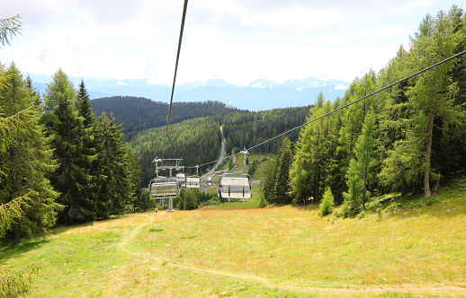 chairlift for the transport of hikers in the high mountains that crosses the forest in summer