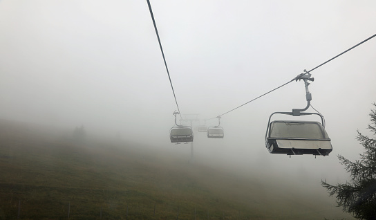 closed chairlift without people immersed in fog in the mountains