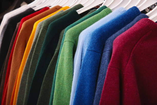 warme pullover. herbst- und winterkleidung. metallregal mit verschiedenen pullovern auf kleiderbügeln in moderner modeboutique - cashmere texture stock-fotos und bilder
