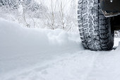 Close-up of a rear black tire in the snow creating tracks