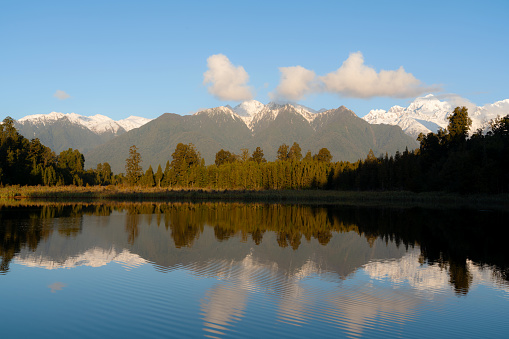 Spectacular Lake Matheson on New Zealand's South Island. In the distance we see clouds languidly drifting across the face of the snowcapped Southern Alps.