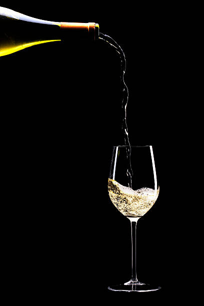 vino blanco siendo vertido en un vaso - wine pouring wineglass white wine fotografías e imágenes de stock