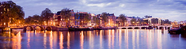 The River Amstel and the traditional canal houses in Amsterdam at dusk. The Magere Brug (Skinny Bridge) can be seen on the far right.