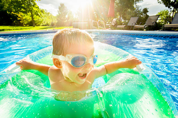 linda little boy en la piscina - bebe bañandose fotografías e imágenes de stock