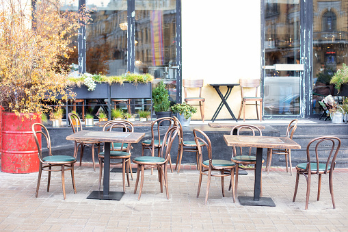 Empty cafe with terrace with tables and wooden chairs. Street vintage exterior of restaurant. Furniture for coffee shop in street in Europe. Typical view of Parisian street with tables of cafe