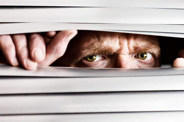 istock Desperate frowning man peeping out through venetian blinds 168445323