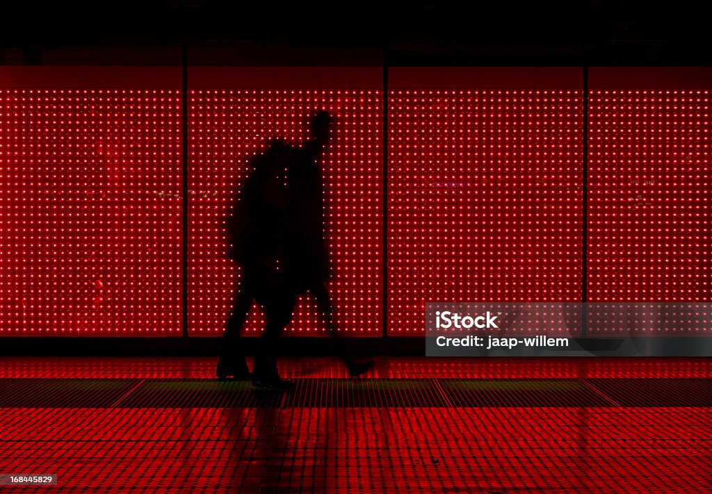 Silhouette of man moving in red background coiuple walking in front of an LED wall Red Stock Photo