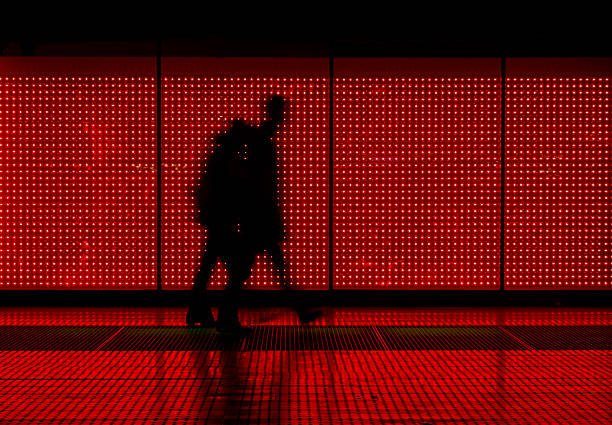Silhouette of man moving in red background coiuple walking in front of an LED wall box office photos stock pictures, royalty-free photos & images