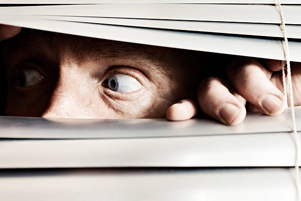 istock Terrified man looks to the side through venetian blinds 168447558