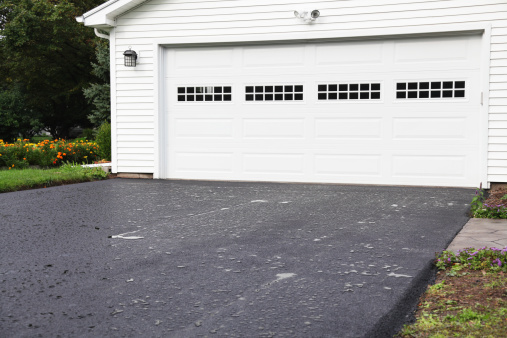 The day after a brand new residential home blacktop asphalt driveway was completed - with overnight rain puddles beading on the still oily surface. This is an \